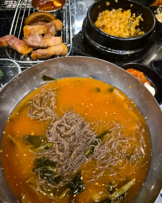 푸짐하게 차려진 고기 한상차림, 가운데에는 시원한 냉면과 밥그릇이 보인다.