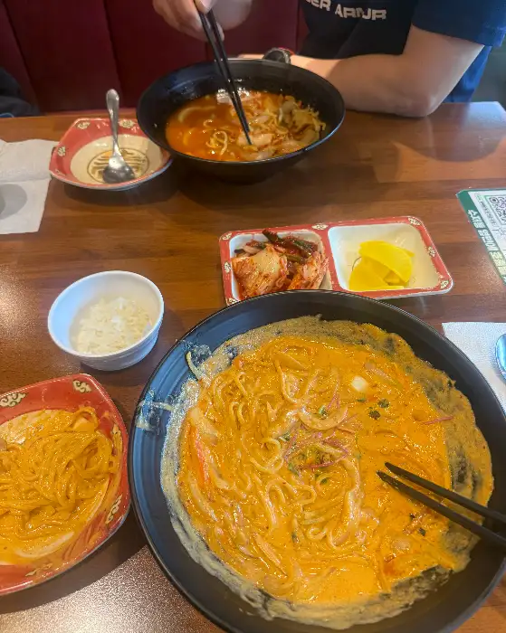 크림 짬뽕이 담긴 커다란 그릇과 그 옆에 놓인 작은 밥그릇, 김치와 단무지