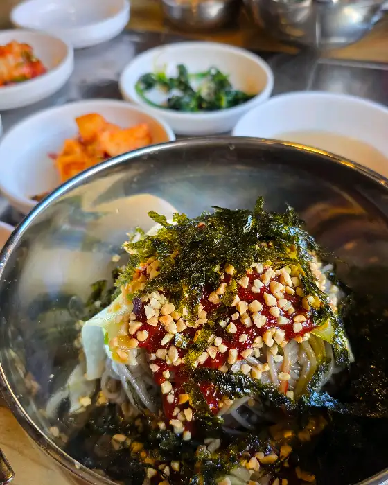 막국수 위에 뿌려진 김가루와 땅콩