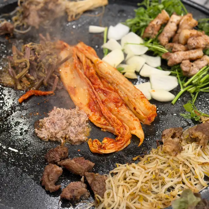돌판 위에서 익어가는 고기와 채소, 김치