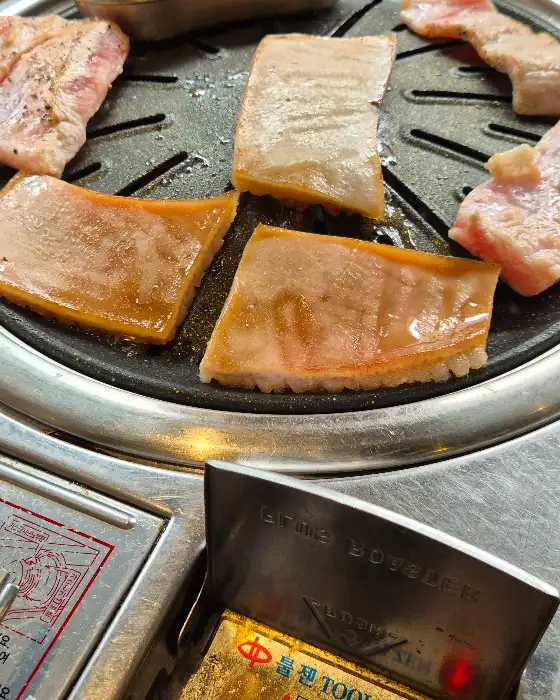 불판 위에 가지런히 놓인 두툼한 고기 껍데기 부분. 바삭하게 익기 직전의 모습이다.
