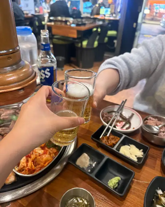 두 사람이 맥주잔을 부딪히며 건배하는 모습.