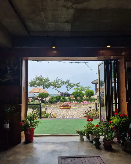 카페 창밖으로 보이는 풍경, 푸른 잔디와 나무, 그리고 바다.