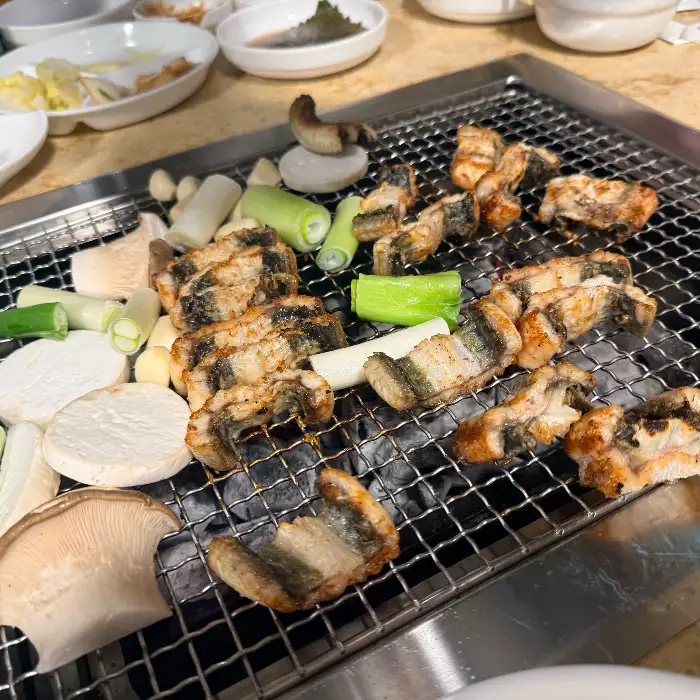 잘 구워진 장어 조각들과 함께 놓인 대파와 버섯