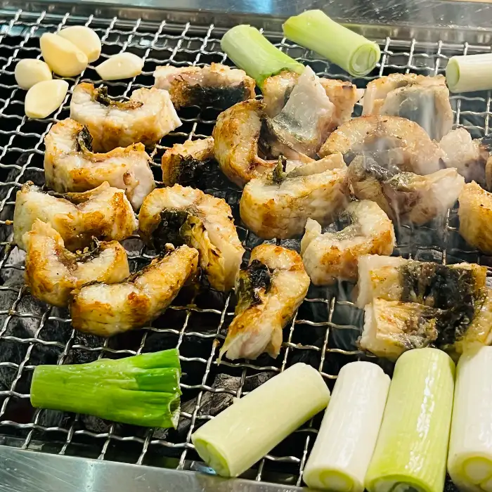 숯불 위에서 구워지고 있는 두툼한 장어 조각들