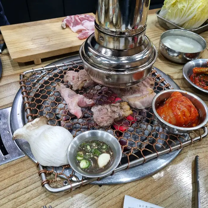 숯불 위에서 지글거리는 고기와 곁들임 반찬