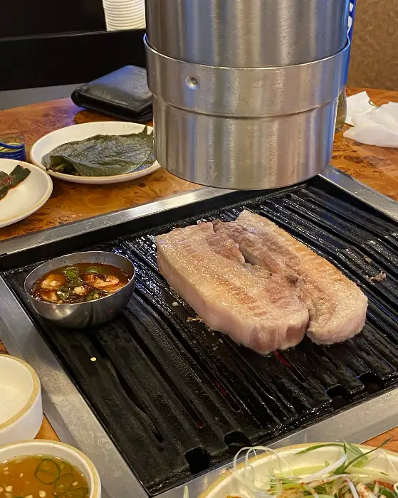 숯불 위에서 구워지고 있는 두툼한 흑돼지 삼겹살