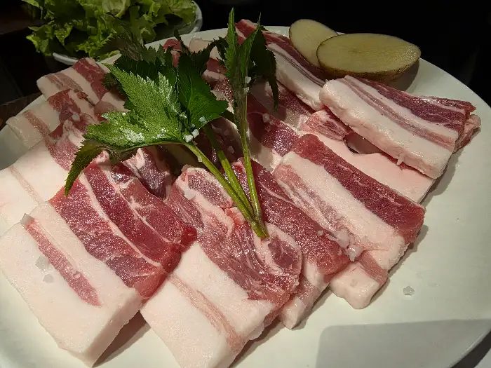접시에 정갈하게 담겨 나온 신선한 생삼겹살과 곁들임 채소