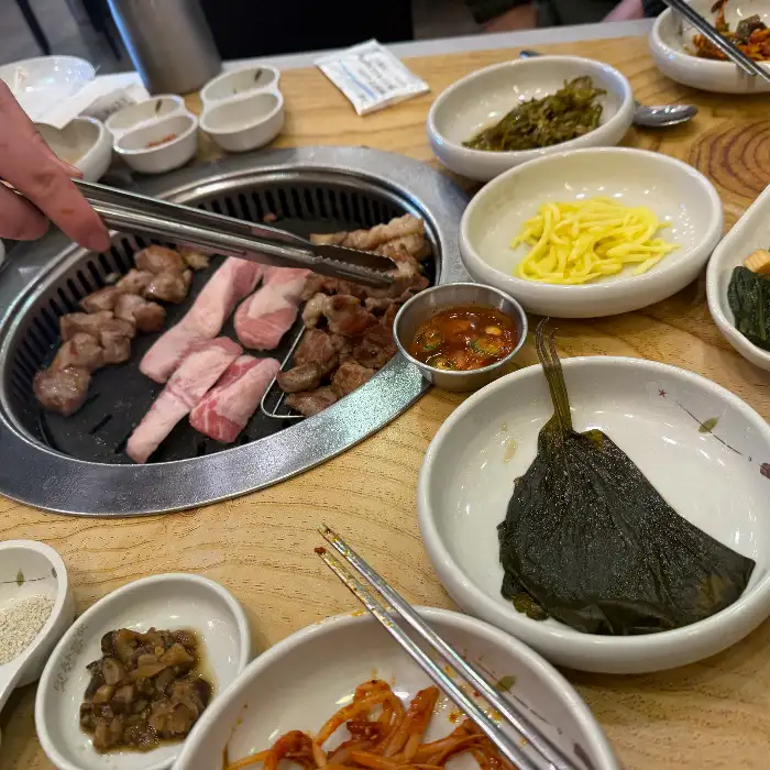 정갈하게 차려진 밑반찬과 불판 위 고기