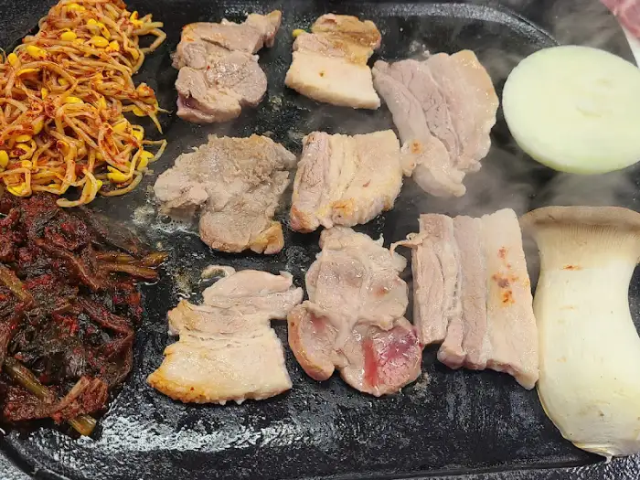 돌판 위에서 익어가는 삼겹살과 곁들임 메뉴