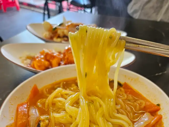 집게로 들어 올린 짬뽕 면발의 쫄깃한 질감
