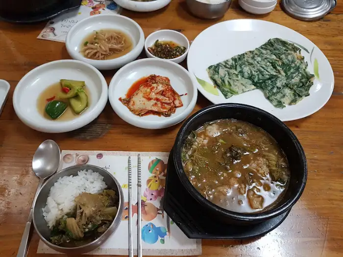 테이블 위에 차려진 추어탕, 밥, 그리고 다양한 밑반찬들