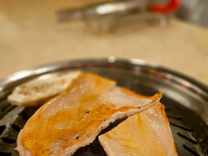 노릇하게 구워진 삼겹살 조각들이 불판 위에서 빛나고 있습니다.