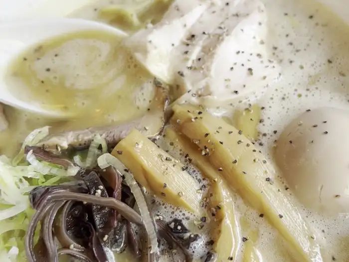 크리미한 국물 위로 보이는 부드러운 닭고기 토핑과 삶은 계란