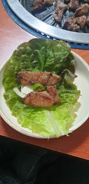 태을갈비에서 쌈 싸 먹는 모습 - 숯불에 구운 갈비를 쌈 채소에 싸서 즐기는 모습