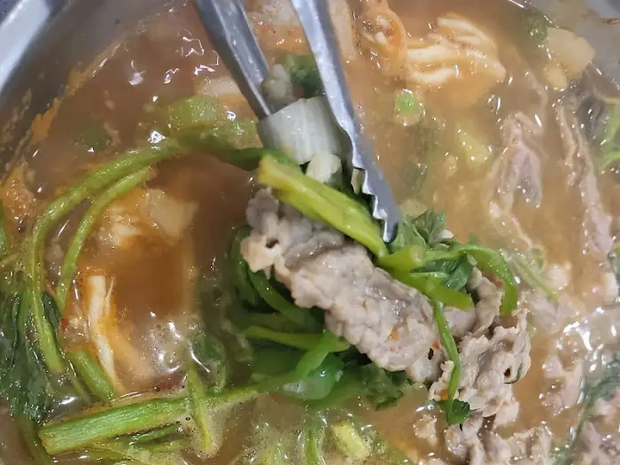 집게로 샤브샤브 고기와 채소를 건져 올리는 모습
