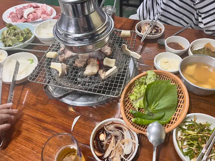 테이블 가득 차려진 맛있는 밑반찬과 쌈채소, 그리고 숯불