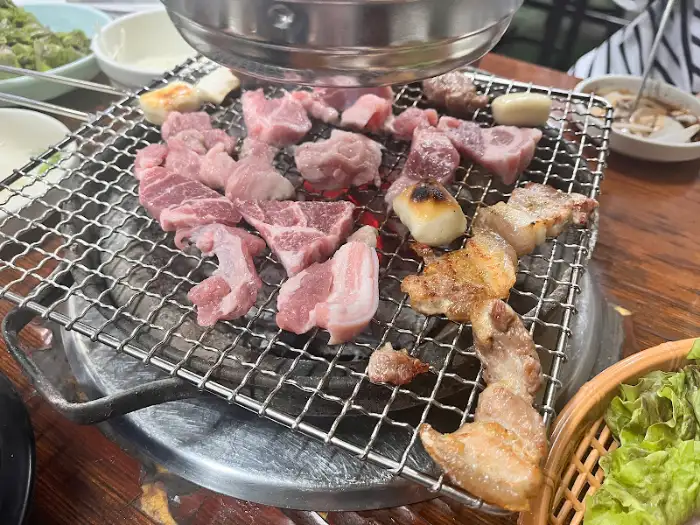 신선한 삼겹살과 목살이 불판 위에서 먹음직스럽게 익어가고 있다.