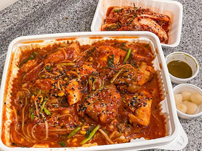 아구찜 양념의 클로즈업. 붉은 양념이 아구살과 콩나물에 풍성하게 묻어 있다.