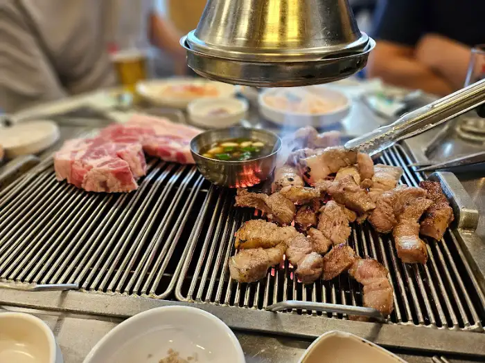 불판 위에서 맛있게 익어가는 흑돼지 목살과 갈매기살