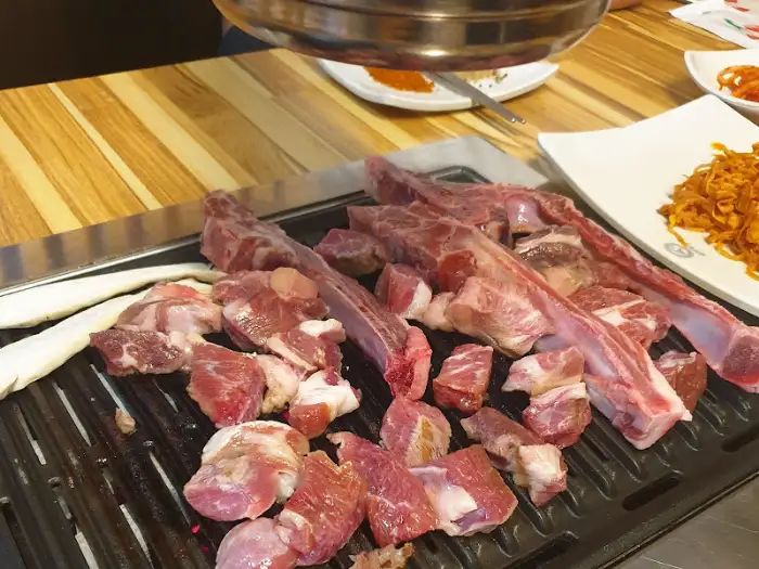 직화 구이 중인 큼직한 양갈비와 작은 접시들