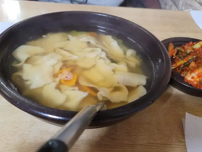 따뜻한 뚝배기에 담긴 수제비와 곁들임 반찬