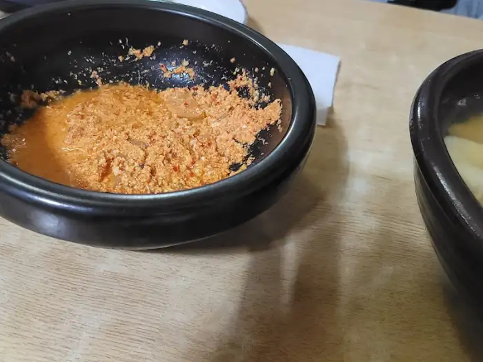 볼록한 검은색 그릇에 담긴 붉은 양념의 콩비지