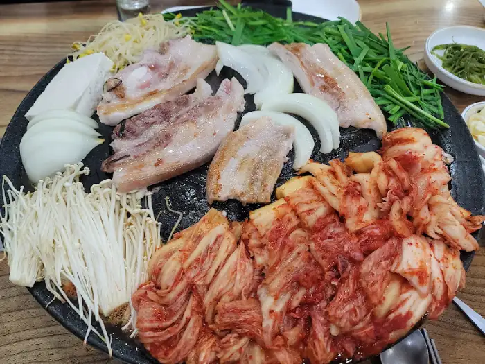 솥뚜껑에 김치와 삼겹살, 버섯이 올라간 모습