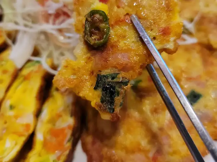 젓가락으로 집어 올린 참치전의 한 조각