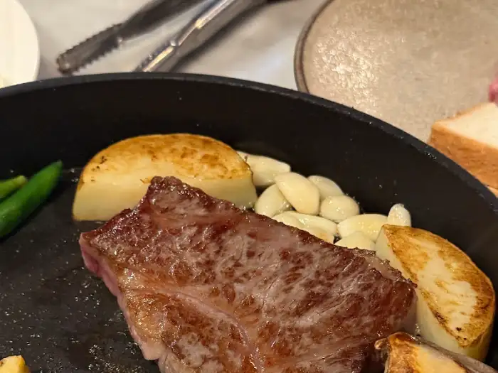팬 위에 올려진 스테이크 조각과 구운 감자, 마늘