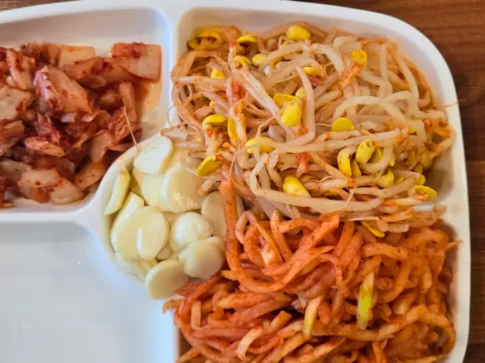 김치, 콩나물, 마늘이 담긴 반찬 접시
