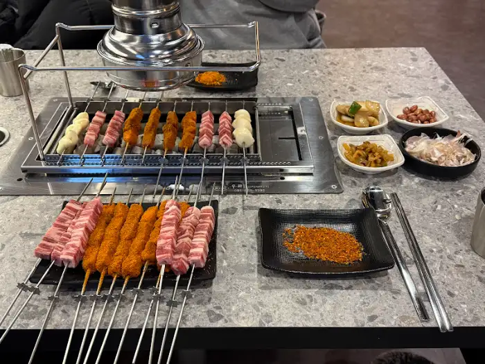 다양한 반찬과 양꼬치, 그리고 양념 가루가 놓인 테이블 상차림