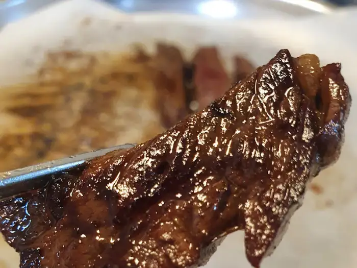 집게로 집어든 스테이크 조각