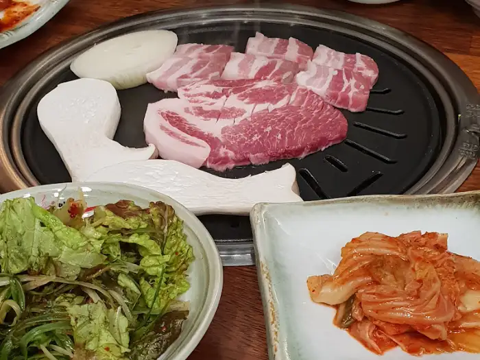 두툼한 돼지갈비와 신선한 야채, 쌈장이 준비된 모습