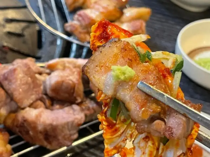 젓가락으로 집은 고추장 양념이 된 고기 덩어리