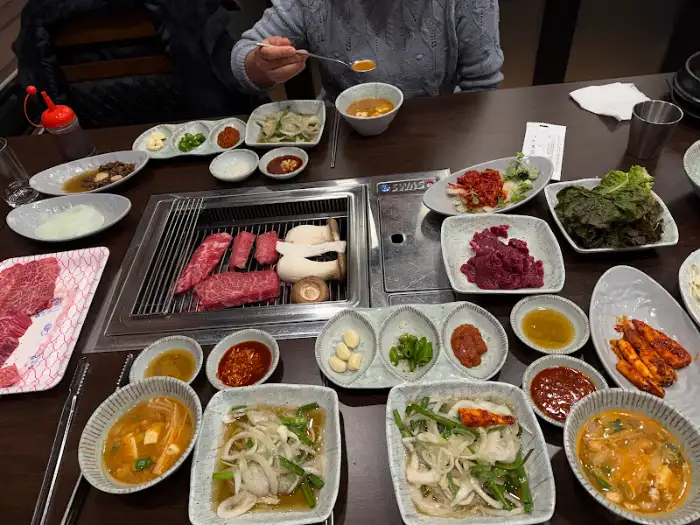 테이블 위에서 구워지고 있는 한우와 버섯, 그리고 다양한 반찬들