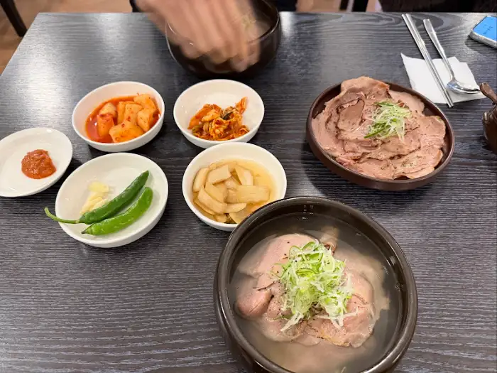 테이블에 놓인 여러 가지 반찬과 돼지곰탕, 수육이 담긴 그릇들.