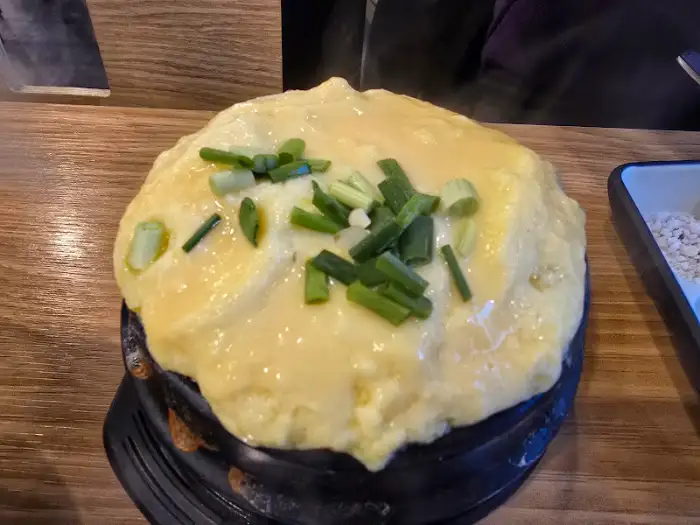 김치찌개가 담긴 뚝배기 위에 파가 뿌려져 있고, 밥과 함께 제공된다.