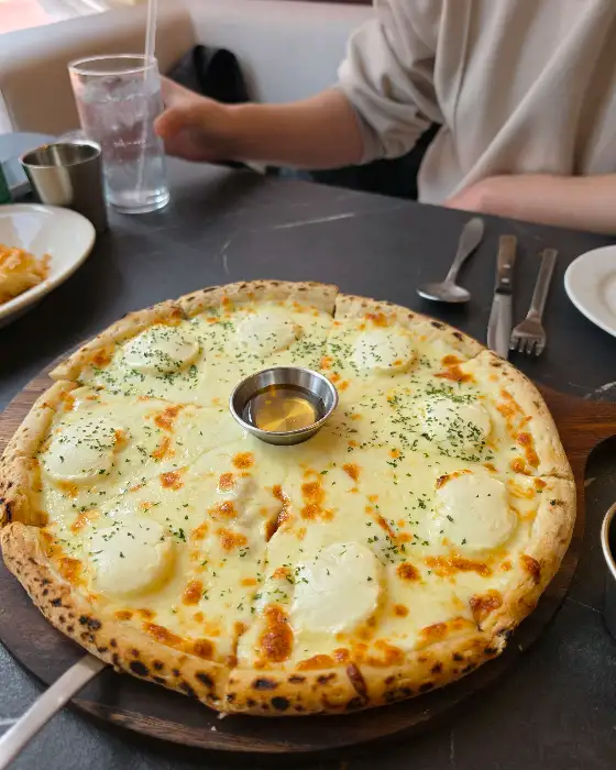 꿀이 담긴 중앙의 작은 그릇과 풍성한 치즈 토핑이 돋보이는 고르곤졸라 피자