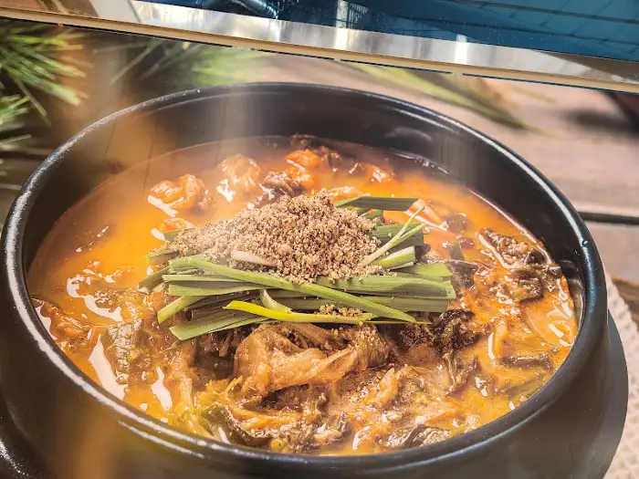뚝배기에 담겨 나온 추어탕, 산처럼 쌓인 다진 마늘과 파가 인상적입니다.