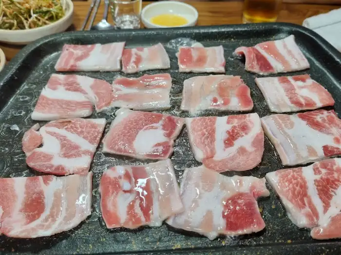 불판 위에 놓인 생삼겹살 조각들