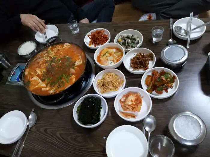 김치찌개와 여러 밑반찬이 놓인 테이블 풍경 (다른 각도)