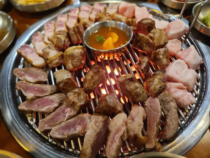 불판 위에 빼곡하게 올라간 초벌 된 목살과 삼겹살