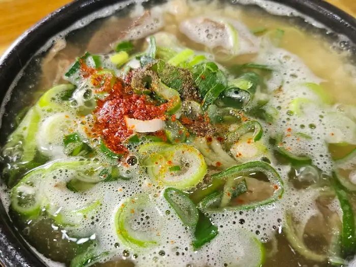 곰탕에 후추와 고춧가루, 파가 듬뿍 뿌려진 모습