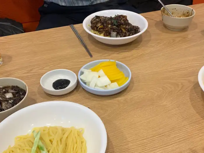 테이블에 놓인 춘장 소스, 단무지, 채 썬 양파 등의 밑반찬