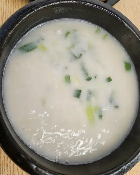 하얀 곰탕 국물에 파와 조각들이 섞여 있는 모습