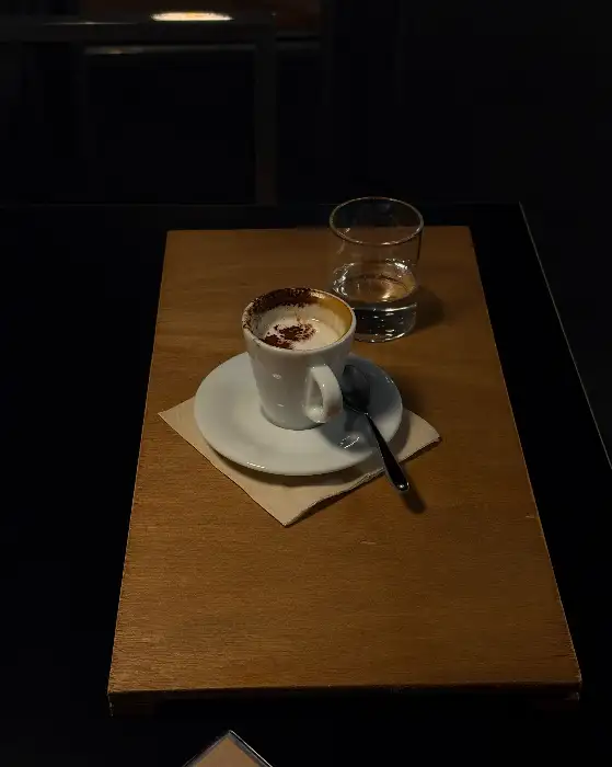 잔에 담긴 커피와 물잔, 그리고 나무 트레이가 보입니다.