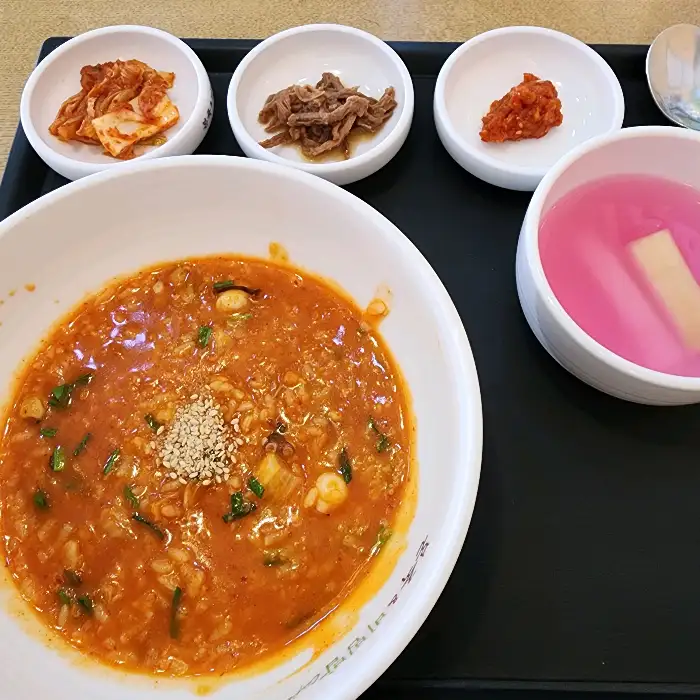 붉은 빛깔의 낙지김치죽과 밑반찬, 동치미