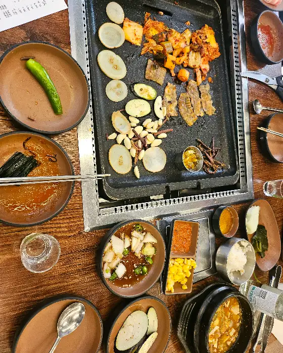 불판 위에서 익어가는 삼겹살과 채소들