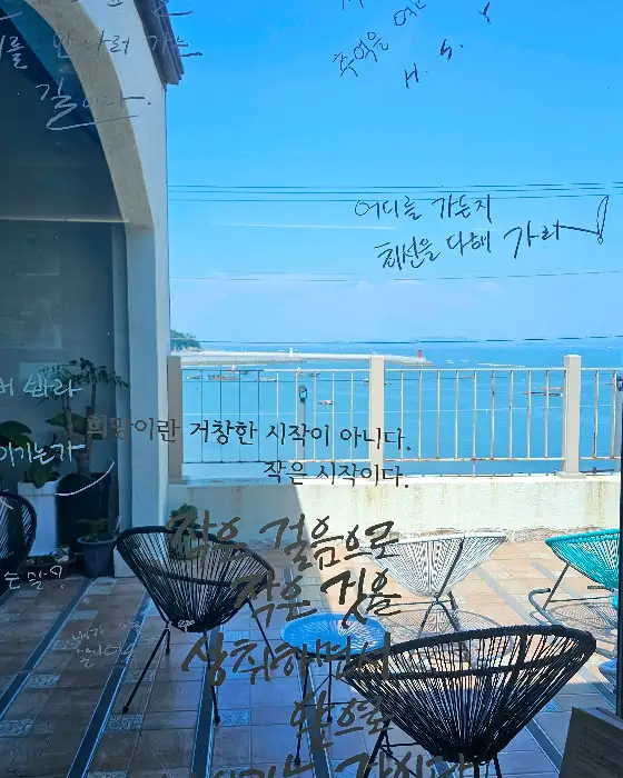창밖으로 보이는 바다 풍경과 유리창 글귀